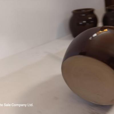 Four small brown crock bowls with embroidered linen