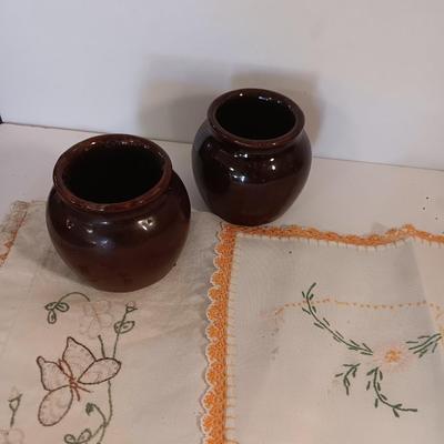 Four small brown crock bowls with embroidered linen