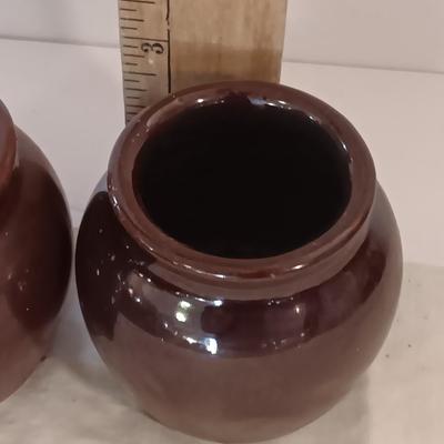 Four small brown crock bowls with embroidered linen
