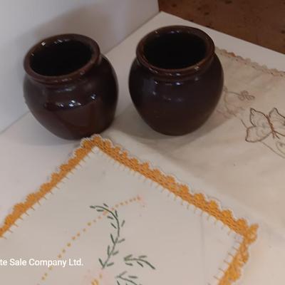 Four small brown crock bowls with embroidered linen