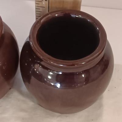 Four small brown crock bowls with embroidered linen