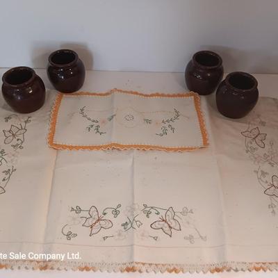 Four small brown crock bowls with embroidered linen