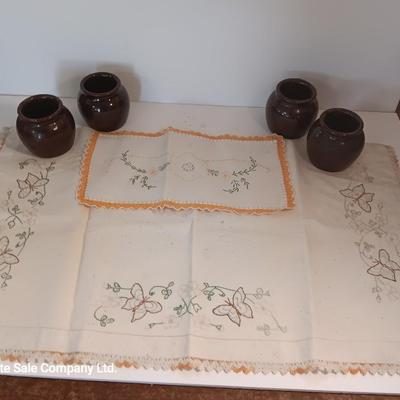Four small brown crock bowls with embroidered linen