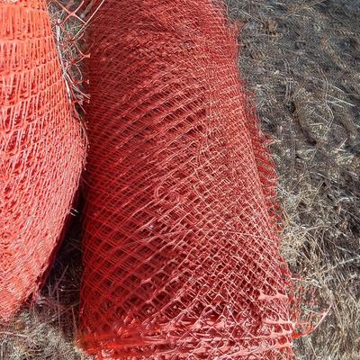 Four rolls of orange construction barrier fencing
