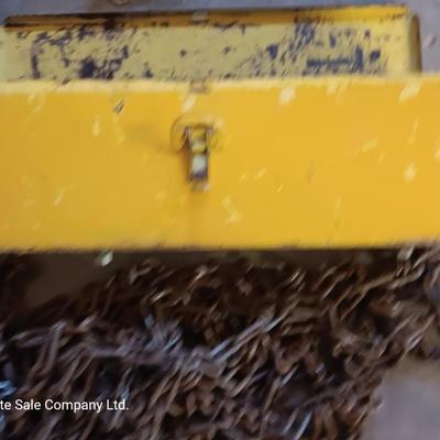Yellow metal toolbox for tractor with assortment of chain and a chain binder