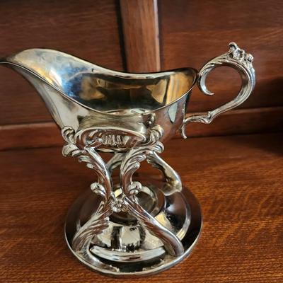 Silver plated tilting gravy boat on a warming stand
