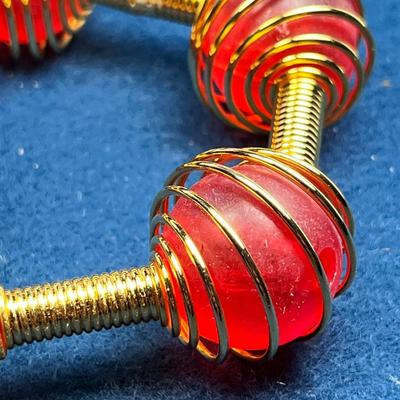 UNUSUAL COILED GOLDTONE BRACELET WITH RED ENCASED BEADS