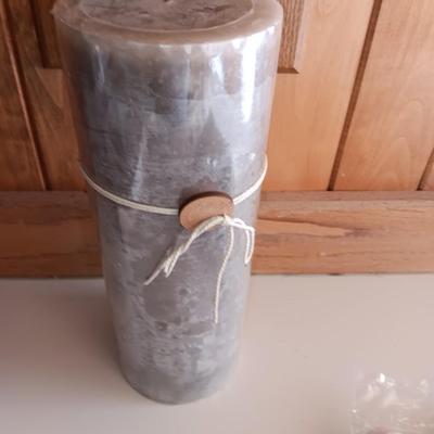 Two unopened bags of 100 ea. unscented tea light candles and a decorative pillar candle