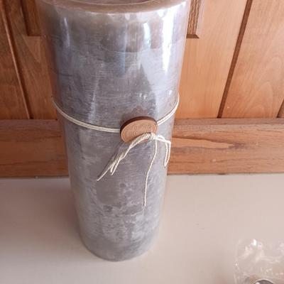 Two unopened bags of 100 ea. unscented tea light candles and a decorative pillar candle