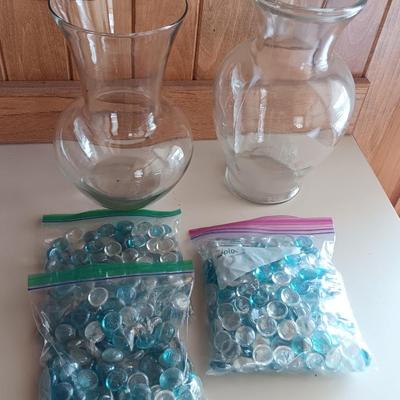 Two tall clear vases with blue toned and clear glass pebbles