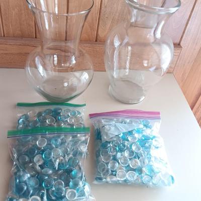 Two tall clear vases with blue toned and clear glass pebbles