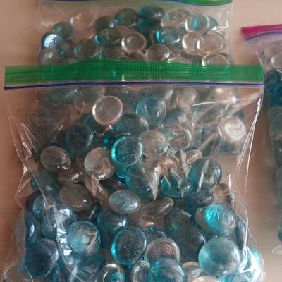 Two tall clear vases with blue toned and clear glass pebbles