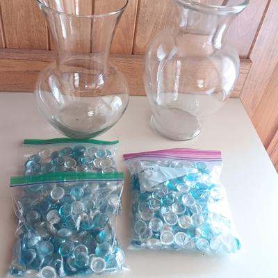 Two tall clear vases with blue toned and clear glass pebbles