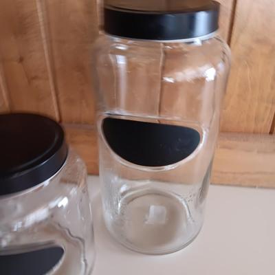 Three glass canisters with lids and chalkboard label area
