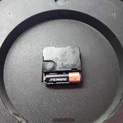 Roman numeral wall clock with woven metal vase decor