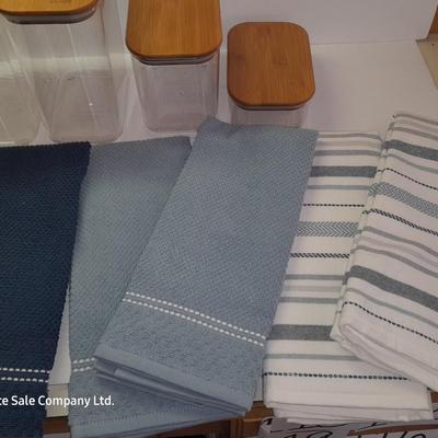 Four wooden bamboo lidded plastic food storage containers with an assortment of Kitchen hand towels