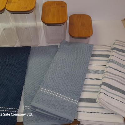 Four wooden bamboo lidded plastic food storage containers with an assortment of Kitchen hand towels