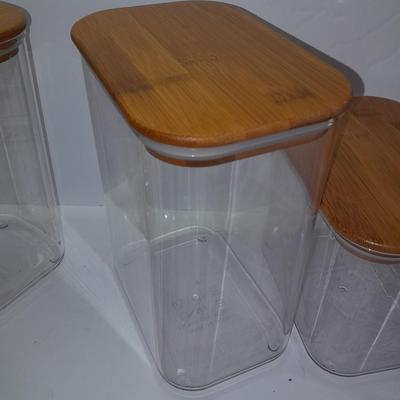 Four wooden bamboo lidded plastic food storage containers with an assortment of Kitchen hand towels