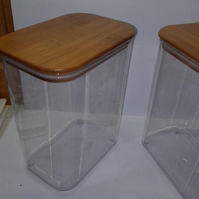 Four wooden bamboo lidded plastic food storage containers with an assortment of Kitchen hand towels