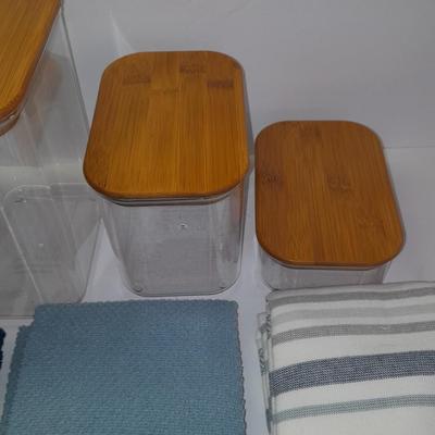Four wooden bamboo lidded plastic food storage containers with an assortment of Kitchen hand towels