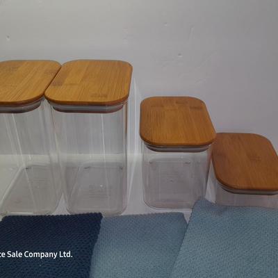 Four wooden bamboo lidded plastic food storage containers with an assortment of Kitchen hand towels