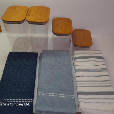 Four wooden bamboo lidded plastic food storage containers with an assortment of Kitchen hand towels