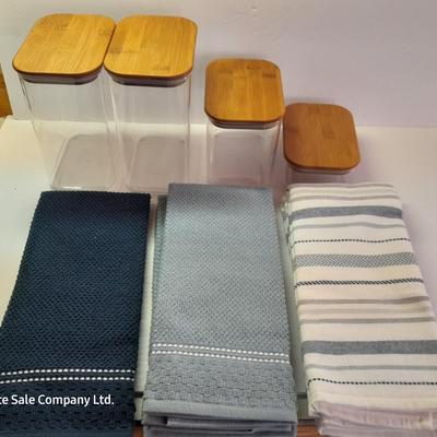 Four wooden bamboo lidded plastic food storage containers with an assortment of Kitchen hand towels