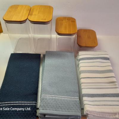 Four wooden bamboo lidded plastic food storage containers with an assortment of Kitchen hand towels