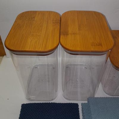 Four wooden bamboo lidded plastic food storage containers with an assortment of Kitchen hand towels