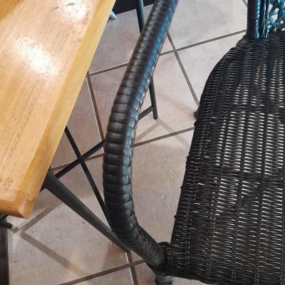 Metal framed end table with wood or glass top and a black woven plastic armchair