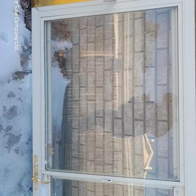 Glass storm door with brass colored trim