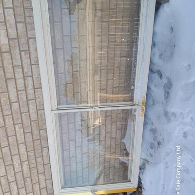 Glass storm door with brass colored trim