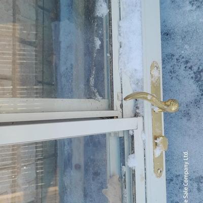 Glass storm door with brass colored trim