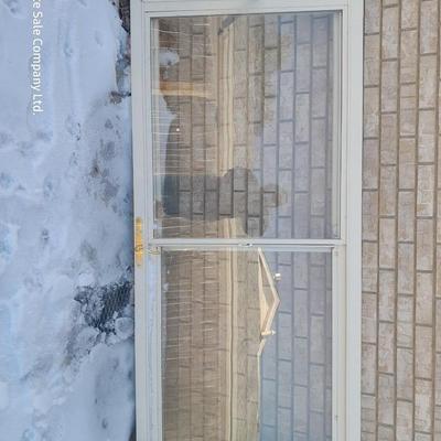 Glass storm door with brass colored trim