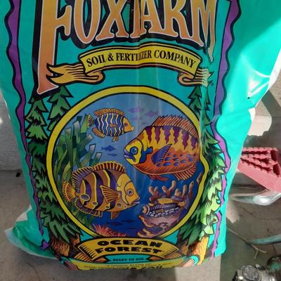 Rope handled barrel with new Fox farm potting soil, weed claw, and other gardening items