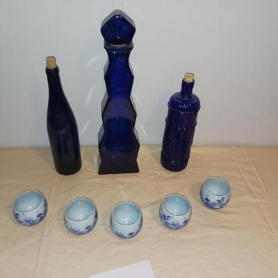 3 BLUE GLASS BOTTLES WITH 5 SIGNED PORCELAIN CUPS
