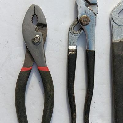 Assortment of black handled Pliers and an adjustable wrench