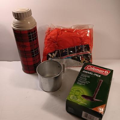 Vintage thermos with raincoat aluminum drinking cup and a folding coleman shovel pick