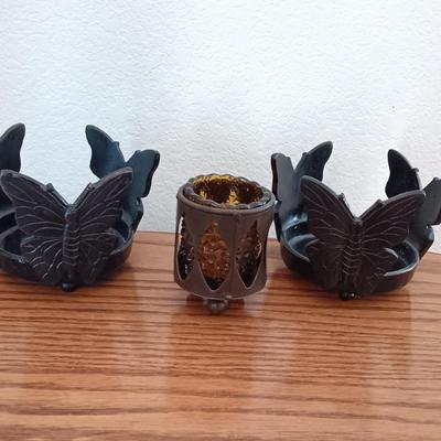 Butterfly pillar candle holders with small metal candle votive with amber glass insert.