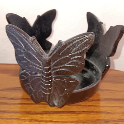 Butterfly pillar candle holders with small metal candle votive with amber glass insert.