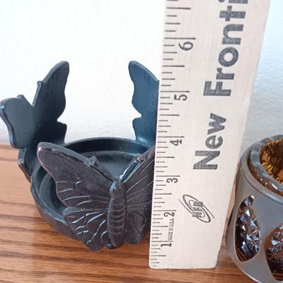 Butterfly pillar candle holders with small metal candle votive with amber glass insert.