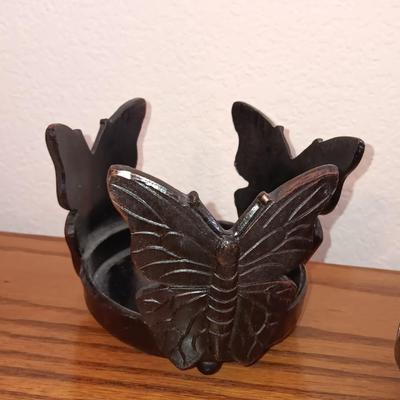 Butterfly pillar candle holders with small metal candle votive with amber glass insert.