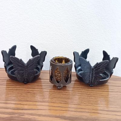 Butterfly pillar candle holders with small metal candle votive with amber glass insert.