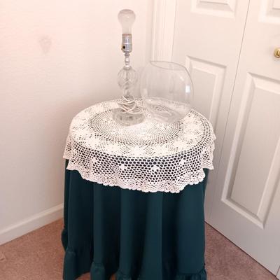 Small covered accent table with vintage lamp and glass vase