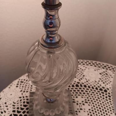 Small covered accent table with vintage lamp and glass vase