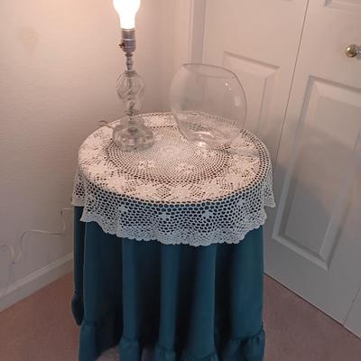 Small covered accent table with vintage lamp and glass vase