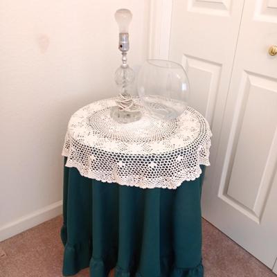 Small covered accent table with vintage lamp and glass vase
