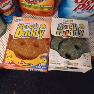Full bottles of cleaning chemicals and two Scrub Daddy scrubbers
