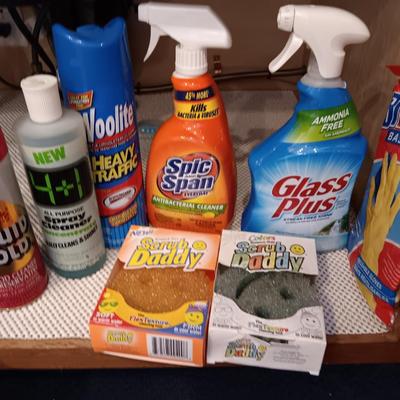 Full bottles of cleaning chemicals and two Scrub Daddy scrubbers