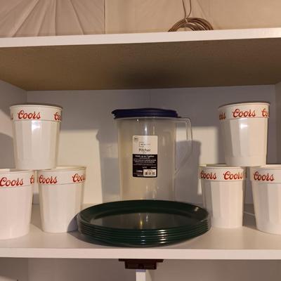 Plastic pitcher with six plastic Coors cups and green plastic plates